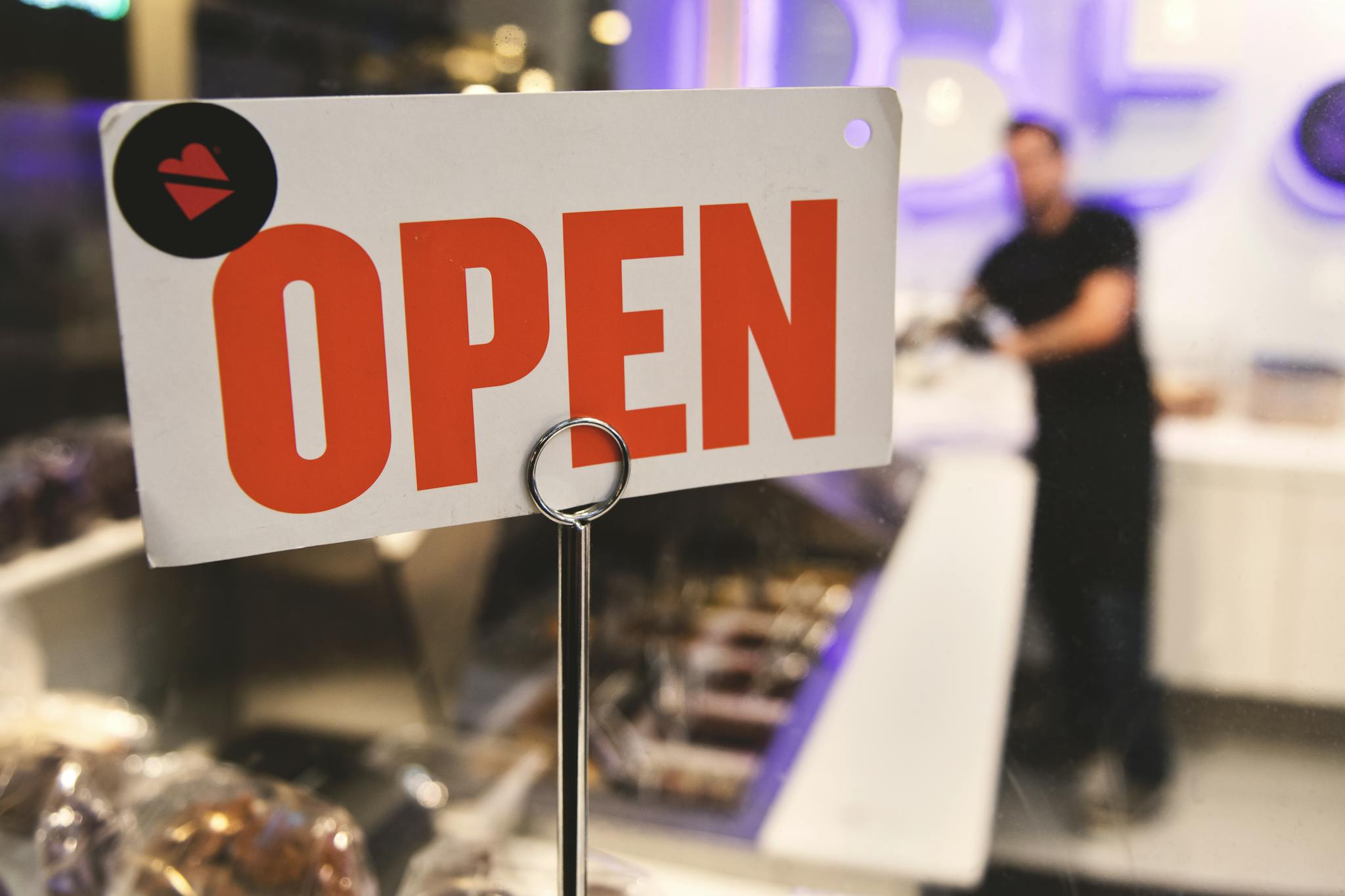 A vibrant open sign in a Los Angeles shop with a blurred figure in the background.